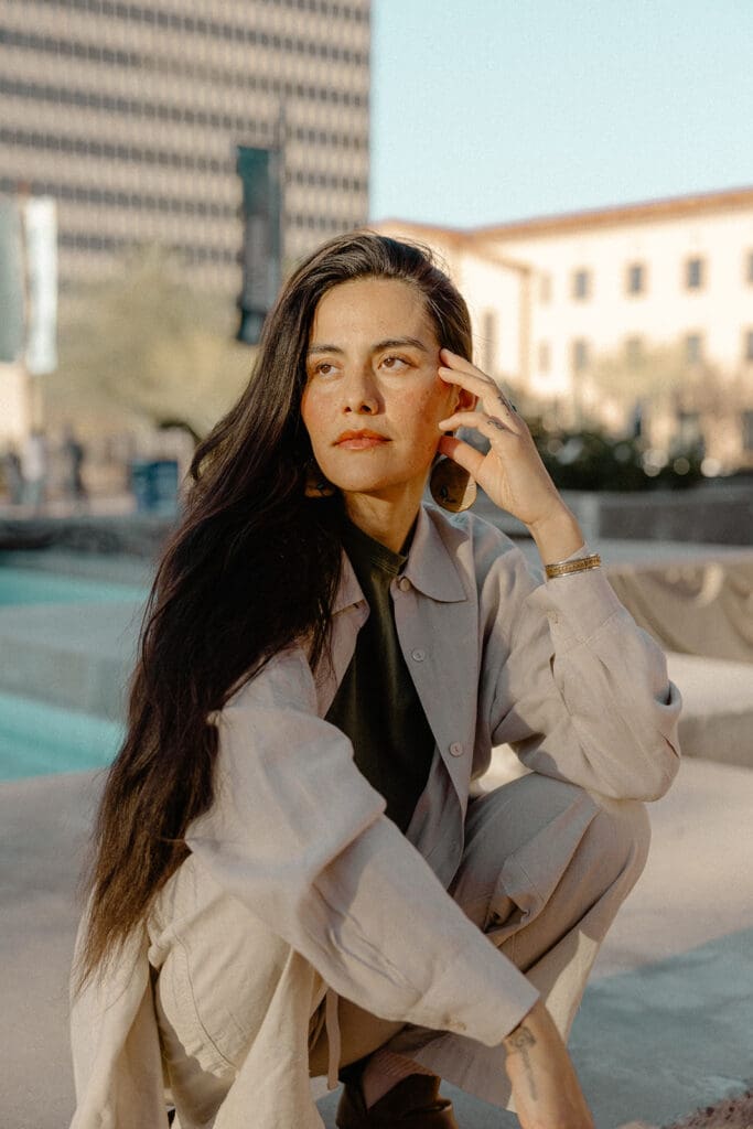 Candid lifestyle portrait crouched near a downtown Tucson fountain in golden light