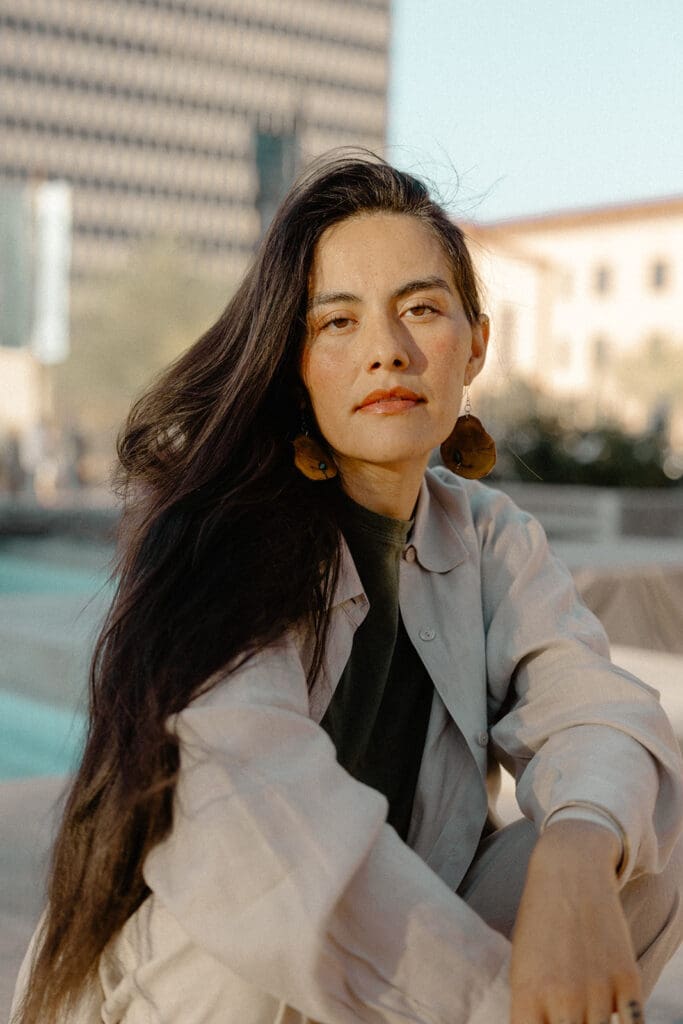 Candid lifestyle portrait crouched near a downtown Tucson fountain in golden light