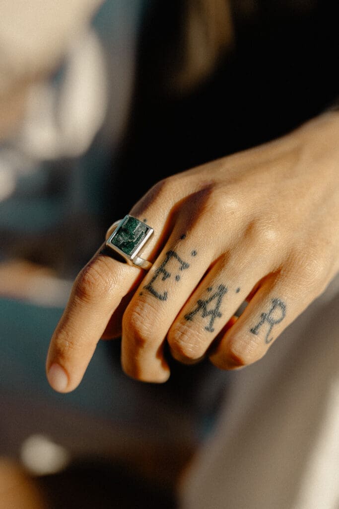 Detail shot of ring and hand tattoos in warm natural light