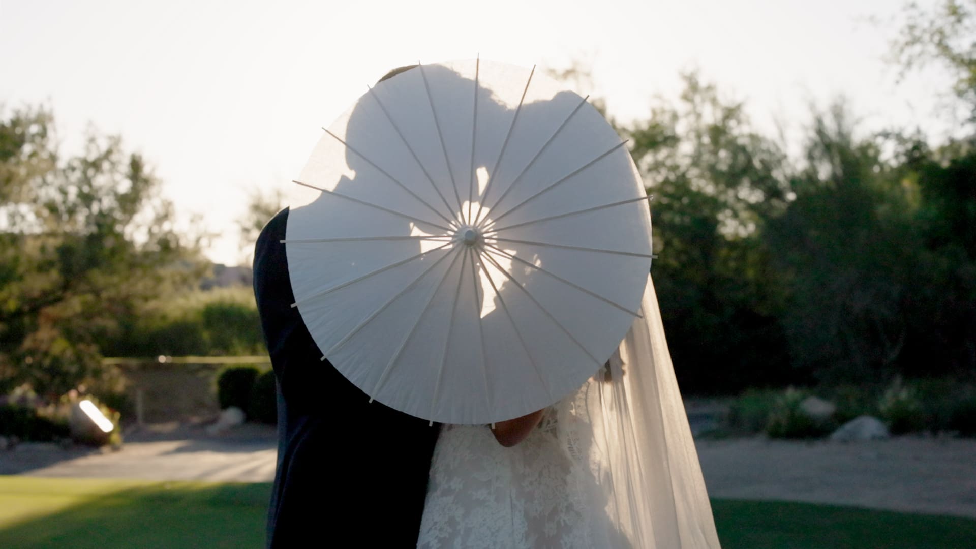 Bride and groom kissing behind a white parasol at a Michigan destination wedding